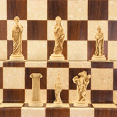 The ivory coloured side of a handmade chess set depicting Roman era figures, displayed on a wooden chess board.