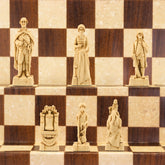 A handmade chess set depicting figures from the American Revolutionary War, placed on a checkered board. The figures include representations of George Washington, Benjamin Franklin, and other historical figures.