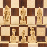 A close-up of a handmade chess set with pieces designed in Viking styles, set up on a wooden chess board.