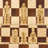 The ivory coloured side of a handmade chess set depicting Shakespeare, Lady Macbeth, Sir John Fallstaff, Nick bottom & The Globe theatre displayed on a wooden chess board.