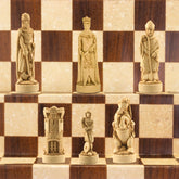A handmade chess set depicting figures from the Battle of Bannockburn, with a checkered background. The set includes a king, a queen, a bishop, a knight, and a rook, all in ivory and burgundy colors.