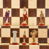 The red side of a handmade chess set with pieces painted in colours and details depicting Roman era figures, displayed on a wooden chess board.