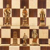 A handmade chess set depicting characters from the Battle of Hastings, with pieces representing King Harold II of England, Edith Swan-Neck, Archbishop Stigand, William the Conqueror, and other Saxon and Norman figures, placed on a checkered background.