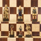 A close-up of a handmade chess set with pieces designed in Viking styles, set up on a wooden chess board.