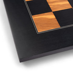 Close-up of a black and wood checkered chess board.