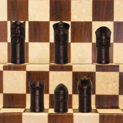 The black coloured side of a hand made chess set inspired by a fusion of traditional staunton chess piece design and medieval masquerades.