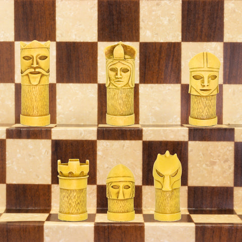 The ivory coloured side of a hand made chess set inspired by a fusion of traditional staunton chess piece design and medieval masquerades.
