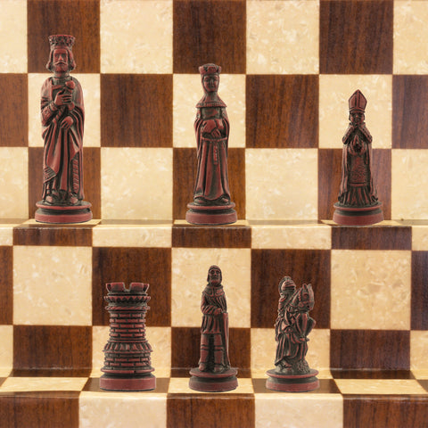 The burgundy coloured side of a handmade miniature chess set with pieces crafted in the design of a typical Western European court in the Middle Ages. The costumes and architecture of the period are faithfully reproduced.
