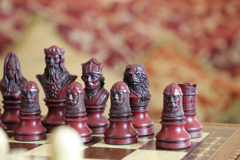 The burgundy coloured side of a hand made themed chess set, designed with a blend of the classic styles of Staunton and the Old French Dieppe, featuring characters such as Richard I as the King, Elanor of Aquitaine as the Queen, Hubert Walder as the Bishop, A Lion as the Knight, and William Marshall as the Pawn.
Placed upon a black and white wooden chessboard.