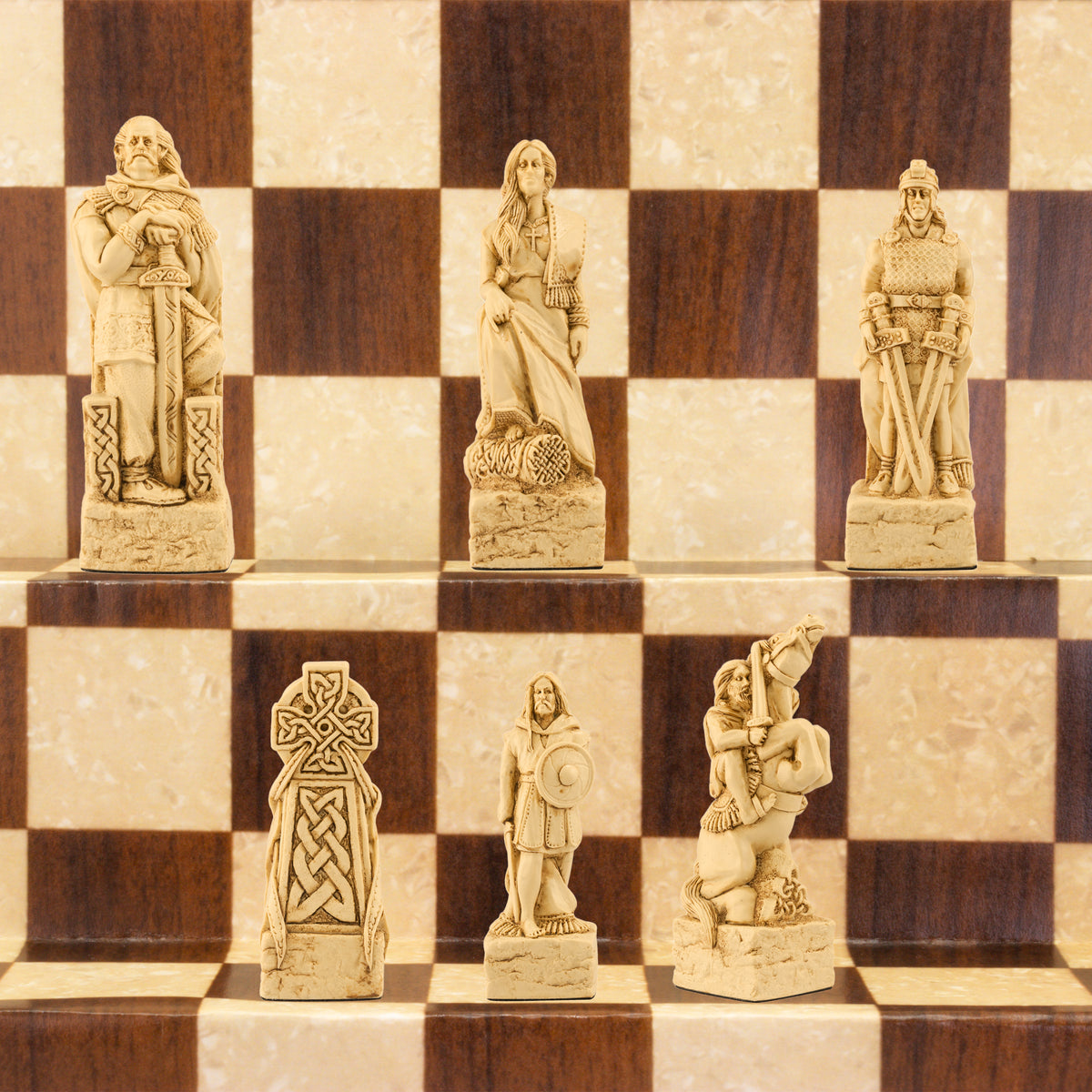A close-up of a handmade chess set with pieces designed in Celtic styles, set up on a wooden chess board.