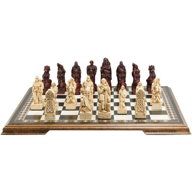 A handmade chess set with pieces designed in Celtic styles, set up on a wooden chess board.