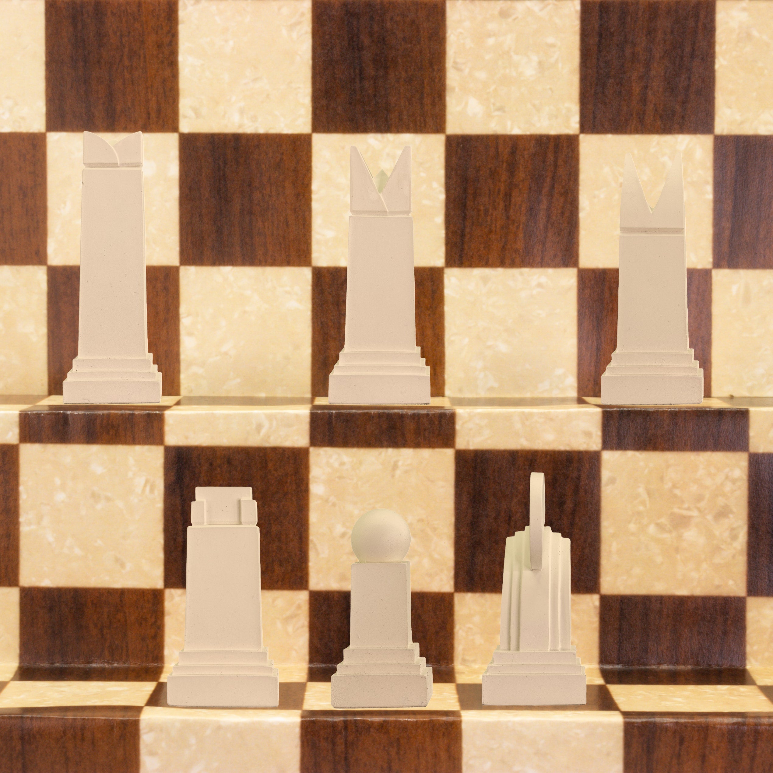 A handmade chess set with pieces in black and white, displayed on a checkered board. The set includes various shapes of pieces, such as rooks, knights, bishops, and pawns, showcasing an Art Deco design style.