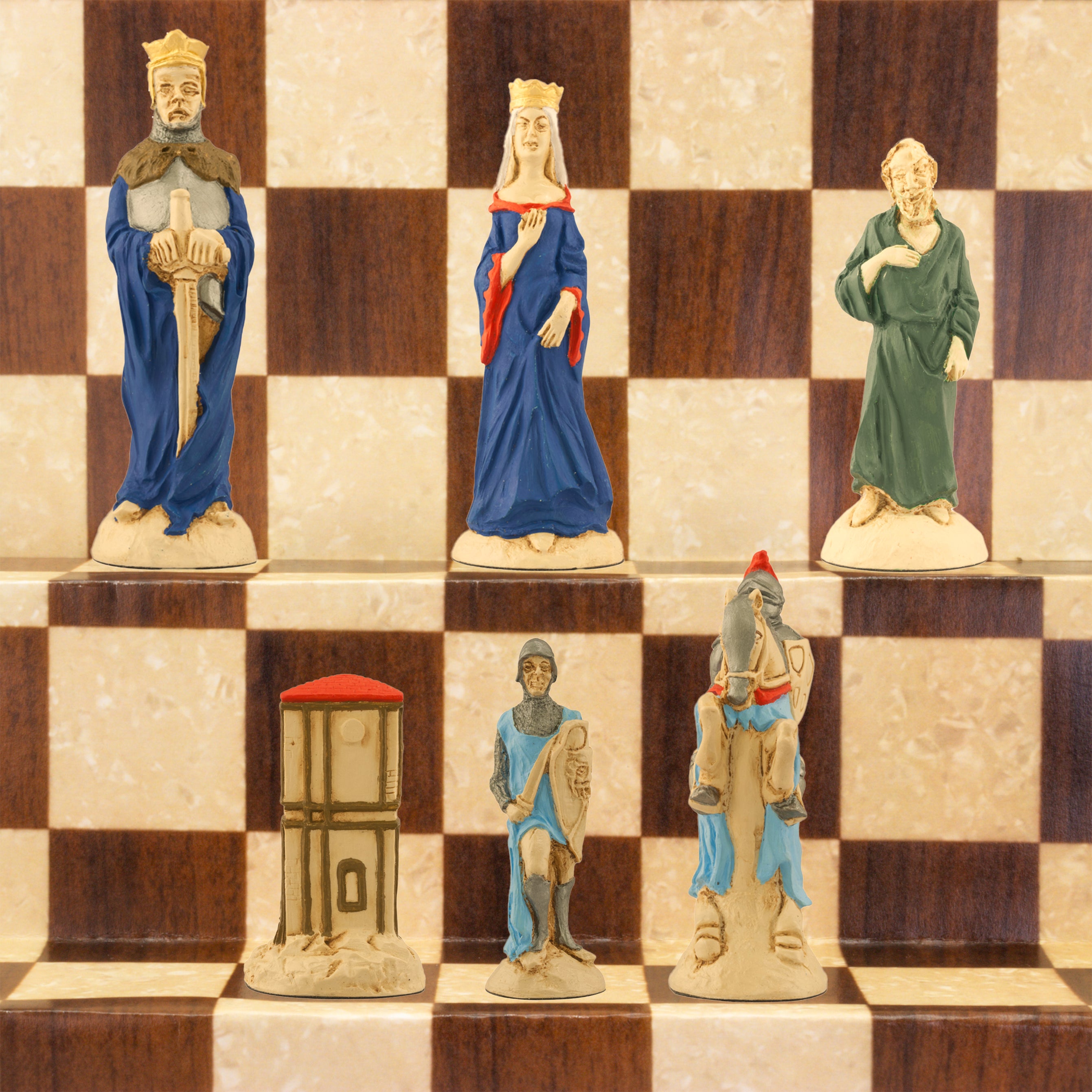 The Blue side of a handpainted chess set featuring characters from the Arthurian legend, placed on a checkered board. The set includes figures representing King Arthur, Queen Guinevere, Merlin the Magician, Sir Lancelot the Knight, & the Castle of Camelot as the rook.