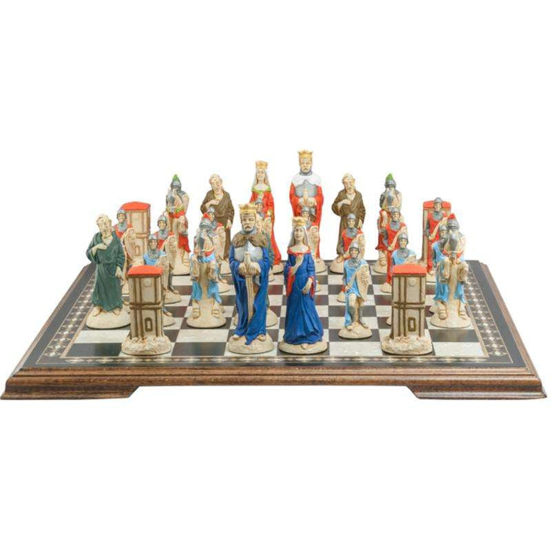 A handpainted chess set featuring characters from the Arthurian legend, placed on a checkered board. The set includes figures representing King Arthur, Queen Guinevere, Merlin the Magician, Sir Lancelot the Knight, & the Castle of Camelot as the rook.