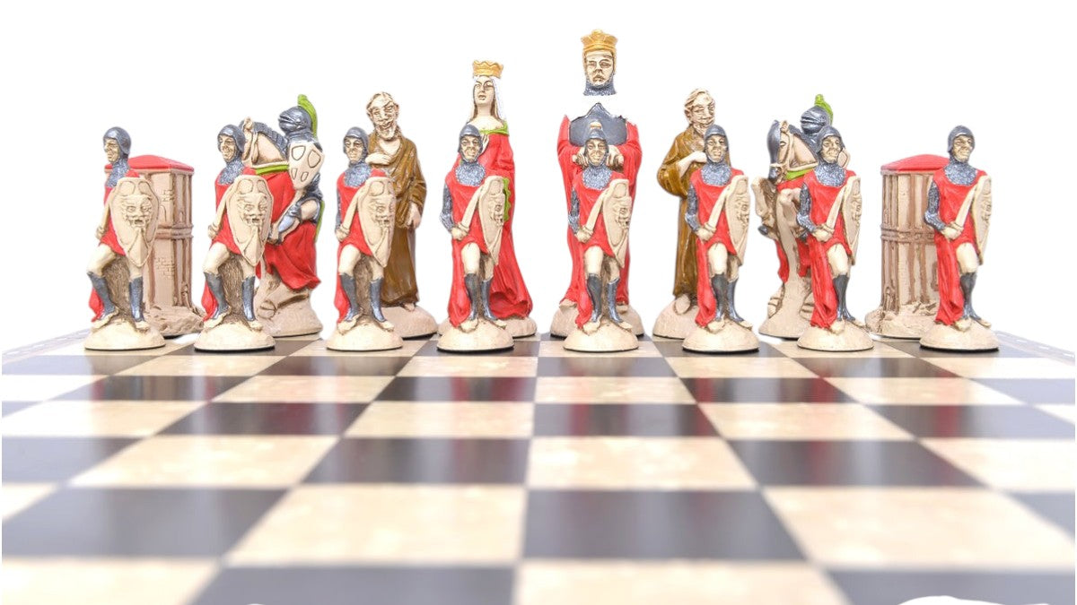 A shot showing the full Red side of a handpainted chess set featuring characters from the Arthurian legend, placed on a checkered board. The set includes figures representing King Arthur, Queen Guinevere, Merlin the Magician, Sir Lancelot the Knight, & the Castle of Camelot as the rook.