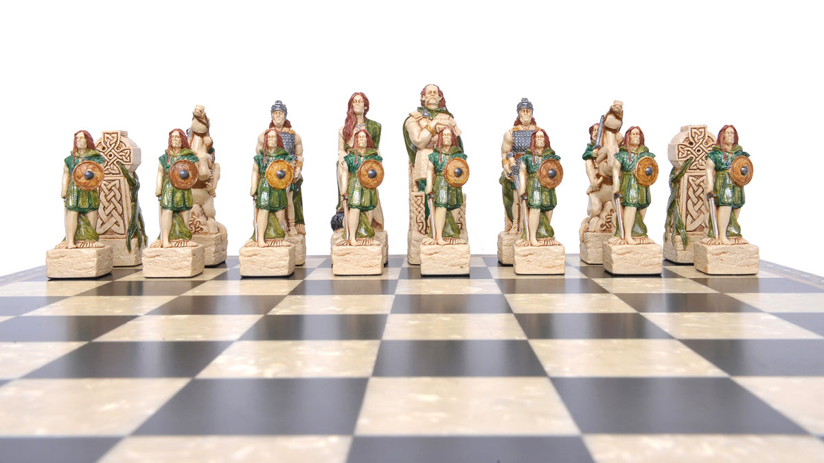 A close-up of a handmade chess set with pieces designed in Celtic styles, set up on a wooden chess board.
