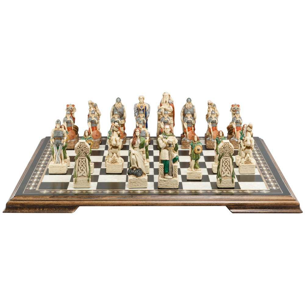 A handmade chess set with pieces designed in Celtic and Viking styles, set up on a wooden chess board.