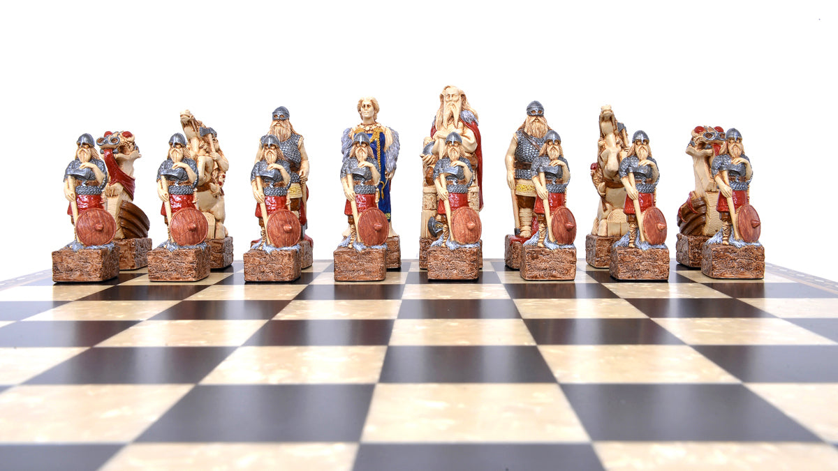 A close-up of a handmade chess set with pieces designed in Viking styles, set up on a wooden chess board.