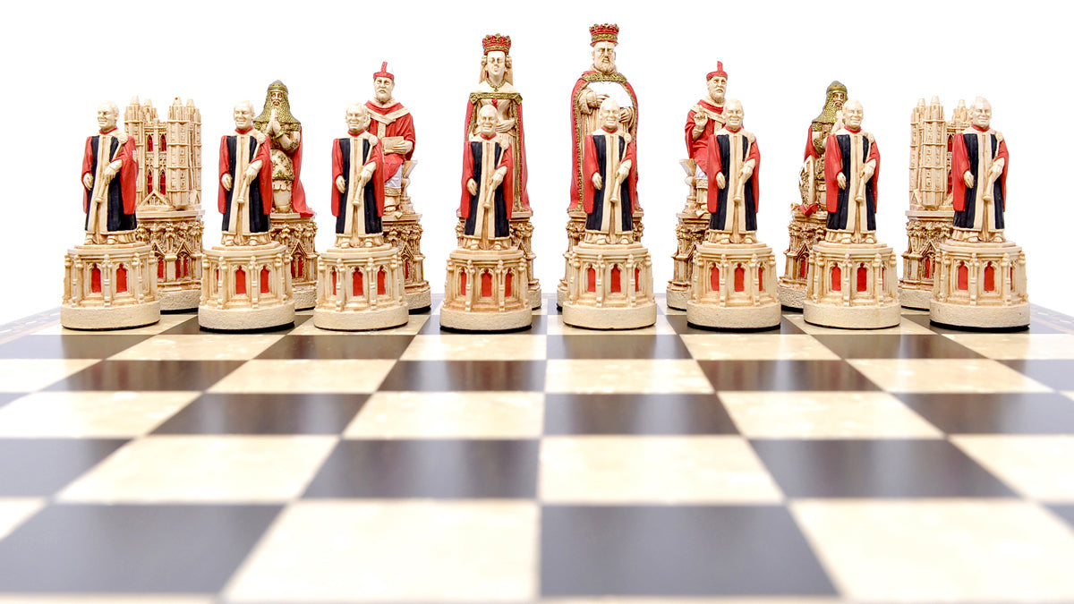 The red coloured side of a hand painted chess set inspired by the architecture and statuary in and around Medieval Cathedrals, a chess set of gracious proportions and great detail, Displayed on a black and white chess board.