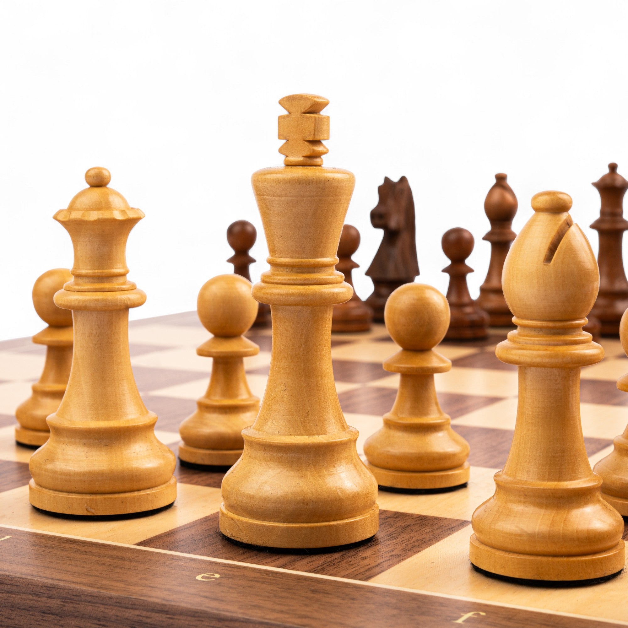 Wooden chess pieces on a chessboard with a white background