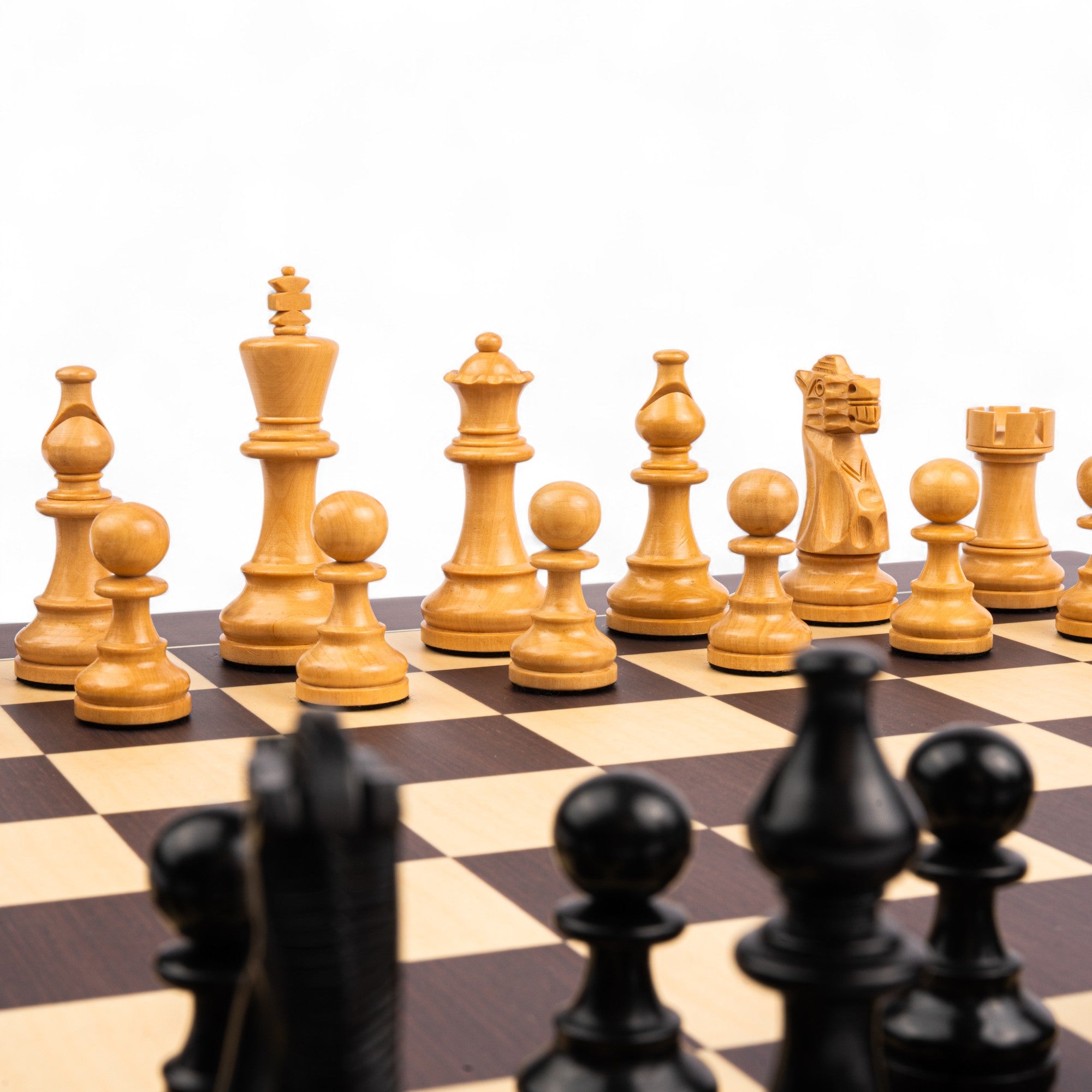 Wooden chess pieces on a chessboard with a white background