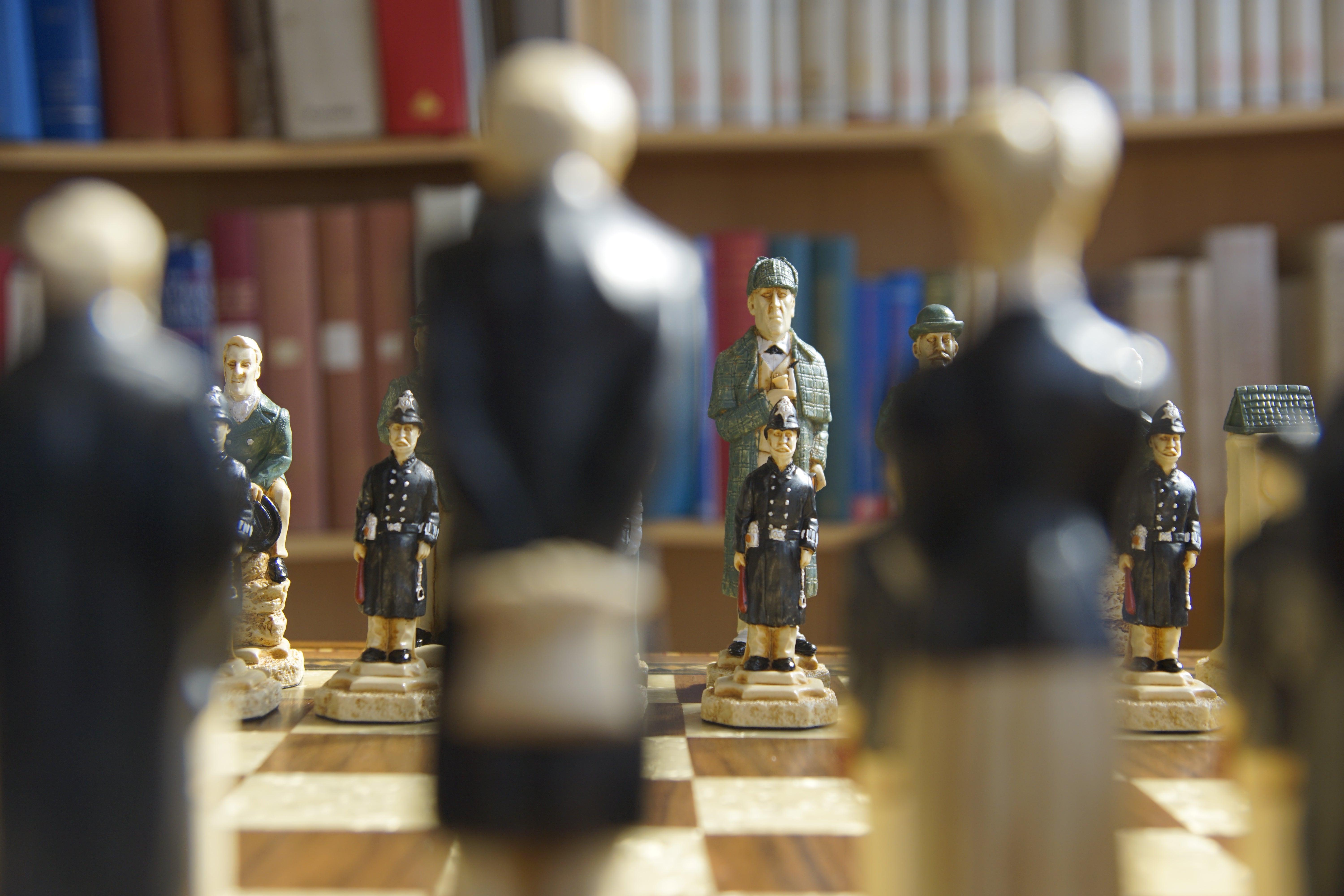 Figures on a chessboard with books in the background